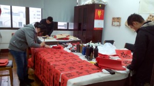 书法社的三位同学在写春联